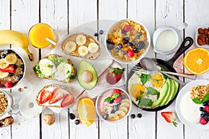 Healthy breakfast table scene with fruits, yogurts, oatmeal, cereal, smoothie bowl, nutritious toasts and egg skillet, top view ov