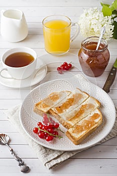 Healthy Breakfast with toast, jam, fresh orange juice and red currants, a Cup of coffee on the white table.