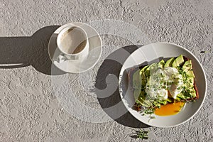 Healthy breakfast, toasted whole grain bread with avocado, poached egg, microgreens and a cup of coffee