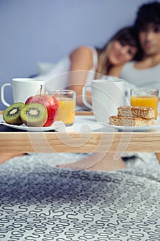 Healthy breakfast on tray and couple lying in