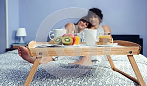 Healthy breakfast on tray and couple lying in