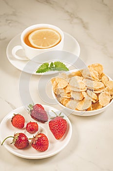 healthy breakfast on a white background/breakfast with strawberry, flakes, honey and tea on a white marble background