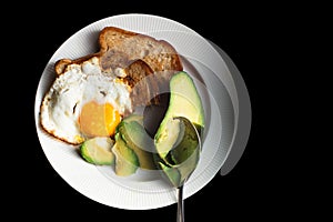 Healthy breakfast on a white plate with toasted bread, avacado and fried eggs