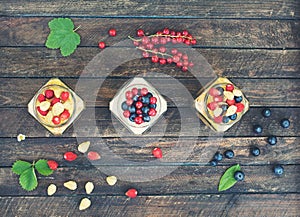 Healthy breakfast. Yogurt and corn flakes with berries in jars on rustic wooden background. Healthy eating and summer gifts