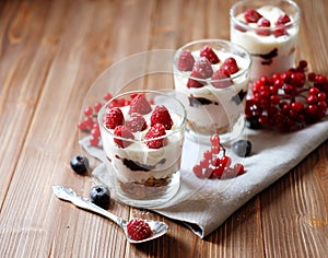 Healthy breakfast - yogurt with fresh berries and muesli served in glass jar, on wooden background