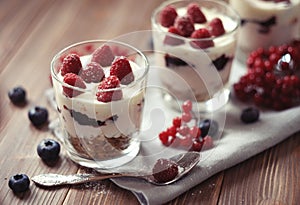 Healthy breakfast - yogurt with fresh berries and muesli served in glass jar, on wooden background