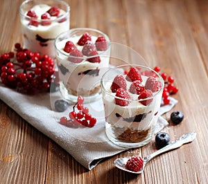 Healthy breakfast - yogurt with fresh berries and muesli served in glass jar, on wooden background