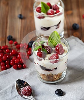 Healthy breakfast - yogurt with fresh berries and muesli served in glass jar, on wooden background
