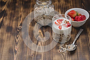 Healthy breakfast. Yogurt, fresh strawberry, homemade granola in open glass jar on a wooden table. Copyspace