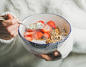 Healthy breakfast yogurt, granola, strawberry bowl in woman`s hands