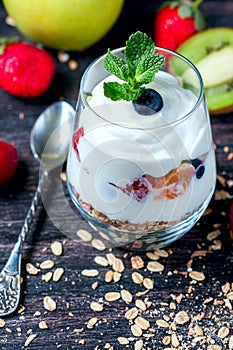 Healthy breakfast - yogurt, muesli, berries and fruits in glass jar. Dark rustic style.