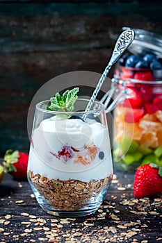 Healthy breakfast - yogurt, muesli, berries and fruits in glass jar. Dark rustic style.