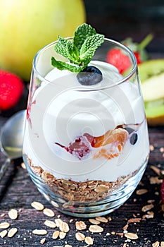 Healthy breakfast - yogurt, muesli, berries and fruits in glass jar. Dark rustic style.