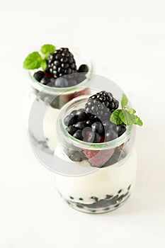 Healthy breakfast: yogurt with strawberry, blueberry and blackberry decorated mint leaves on white wooden table