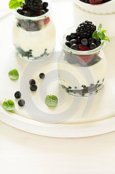 Healthy breakfast: yogurt with strawberry, blueberry and blackberry decorated mint leaves on white wooden table