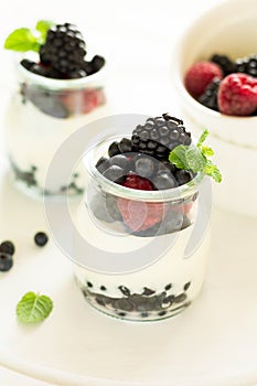 Healthy breakfast: yogurt with strawberry, blueberry and blackberry decorated mint leaves on white wooden table