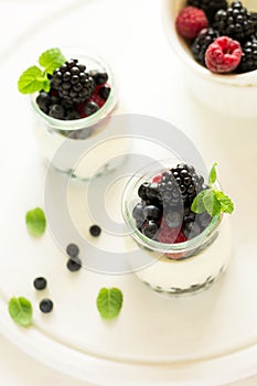 Healthy breakfast: yogurt with strawberry, blueberry and blackberry decorated mint leaves on white wooden table