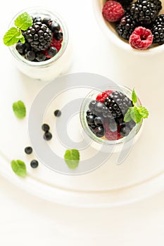 Healthy breakfast: yogurt with strawberry, blueberry and blackberry decorated mint leaves on white wooden table