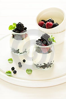 Healthy breakfast: yogurt with strawberry, blueberry and blackberry decorated mint leaves on white wooden table