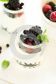 Healthy breakfast: yogurt with strawberry, blueberry and blackberry decorated mint leaves on white wooden table