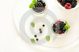 Healthy breakfast: yogurt with strawberry, blueberry and blackberry decorated mint leaves on white wooden table