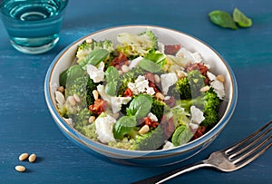 healthy broccoli salad with feta cheese sun dried tomatoes pine nuts.. vegetarian low carb keto diet photo