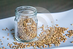 Healthy buckwheat grains in glass jar on white plate