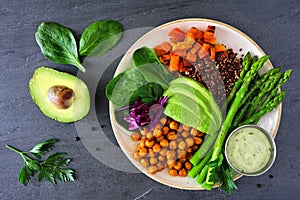 Healthy Buddha bowl with asparagus, quinoa, sweet potato, chickpeas and avocado, top view over slate