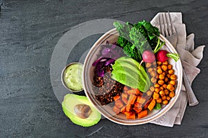 Healthy Buddha bowl with rapini, quinoa, sweet potato, chickpeas and avocado, top view scene over dark slate