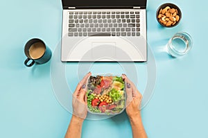 Healthy business lunch in the office, salad for snack, glass of water, almonds, cup of coffee on blue. Top view with copy space. C