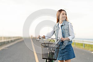 Healthy candid teen girl taking a walk with a bike on the bridge in summer