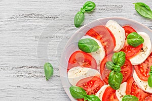 Healthy caprese salad with ripe tomatoes and mozzarella cheese with fresh basil leaves. Italian food. top view