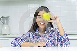 Healthy care diet or fruits concept. Attractive smiling young woman holding fresh green apple covered own eyes breakfast time