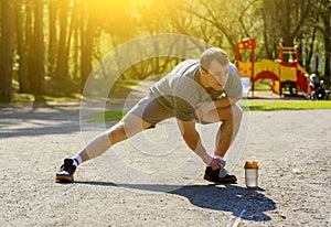 Healthy caucasian sportsman with muscular figure doing stretching exercise before run
