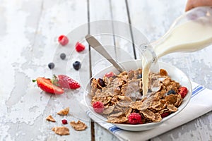 Healthy cereal breakfast. with Berries - fresh strawberries and blueberries, with milk pourring on old wooden table