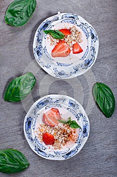 Healthy cereal with strawberries and yogurt decorate with mint in a ceramic bowls on wooden table. Granola, muesli