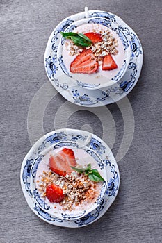 Healthy cereal with strawberries and yogurt decorate with mint in a ceramic bowls on wooden table. Granola, muesli