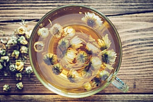 Healthy chamomile tea cup and dry daisy flowers.