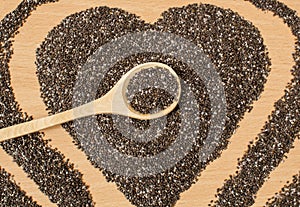 Healthy Chia seeds in the form of a heart. Chia in a wooden spoon on a wooden table close-up.