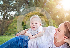 Healthy child (kid) having fun with mother in the sunny summer day at the park. Caucasians happy baby (boy).