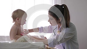 Healthy childhood, professional family doctor female examines nice child boy in bright natural light close up in clinic
