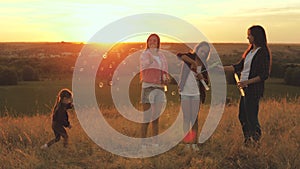 Healthy children and mom play, blow kid catches soap bubbles. mother and sisters play together in the park at sunset