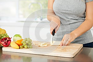 Healthy choices - Diet. Curvaceous young woman chopping fruit in her kitchen - cropped.