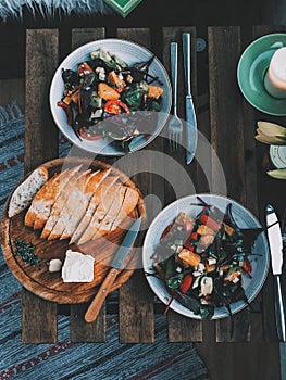 Healthy colorful vegan salad and homemade bread on a vintage wooden table with flowers