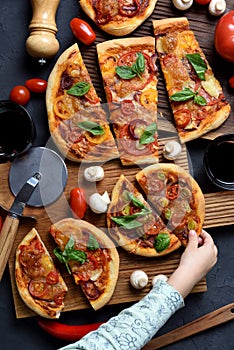 Healthy comfort food. Little child hand reaching for piece of homemade vegetarian pizza with mushrooms and basil on dark