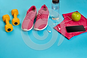 Healthy concept, diet plan with sport shoes and bottle of water and dumbbells on blue background, healthy food and