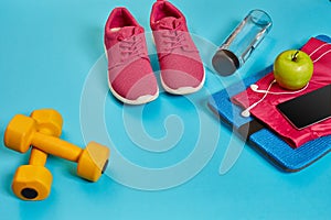 Healthy concept, diet plan with sport shoes and bottle of water and dumbbells on blue background, healthy food and