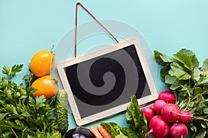 Healthy concept. Fresh vegetables around black desk on blue background.