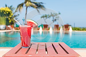 Healthy concept, Water melon smoothie on a wood table with swimming pool and blue sky background