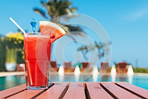 Healthy concept, Water melon smoothie on a wood table with swimming pool and blue sky background